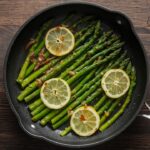 Bestcookhub - Perfectly cooked frozen asparagus in a skillet with lemon and garlic on a wooden table
